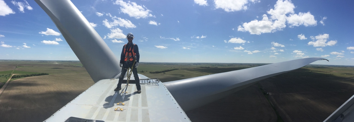 student on top of large wind turbine