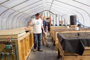 Inside the greenhouse, thermal battery (left) and raised aquaponics grow beds (right)